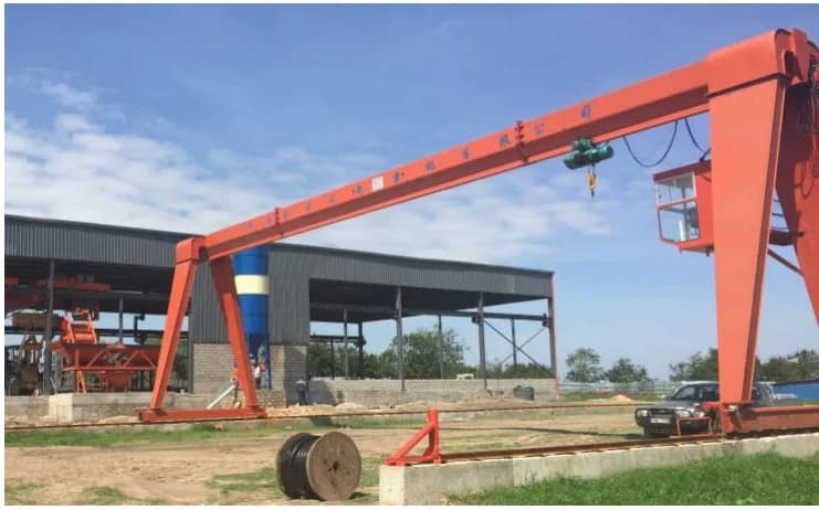 Steel-frame workshop building with profiled metal cladding, served by a gantry crane on rails