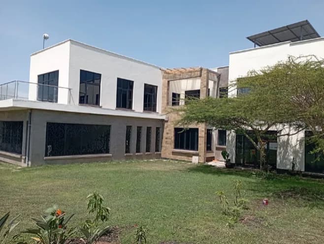 Completed two-storey commercial building with rendered and stone-clad facade, full-height glazing and roof-mounted solar panels